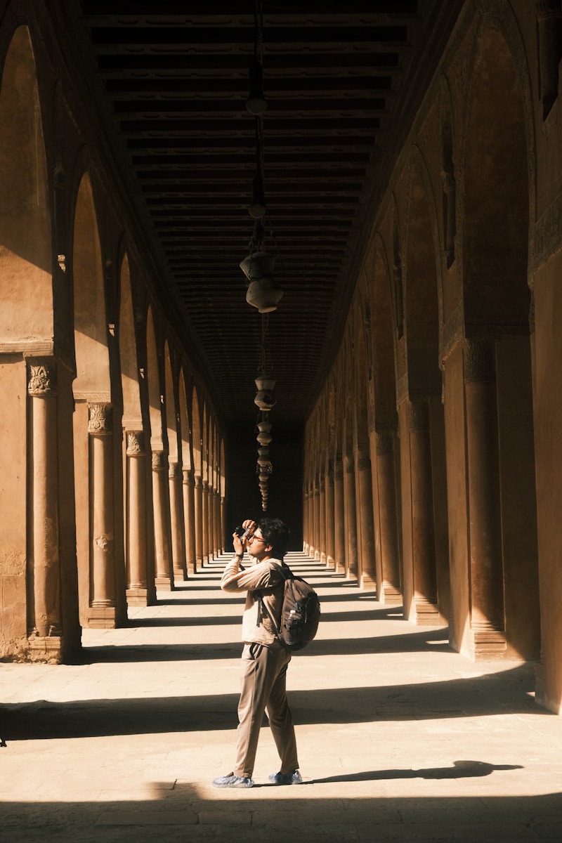 Man photographing ancient arched corridor with sunlight